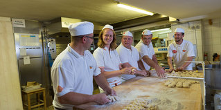 Die Chefin Elisabeth Pernsteiner und vier weitere Bäcker stehen an einem Tisch und formen Brötchen