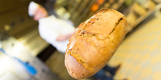 Ein Bäcker hält ein frisches Brot auf einer Schaufel